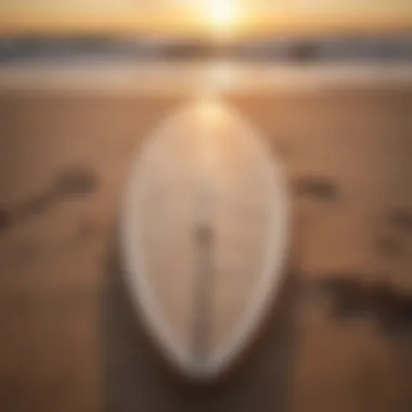 A beautifully shaped surfboard resting on a sandy beach at sunset.