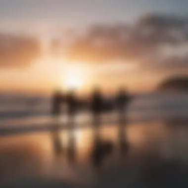 A sunset silhouette of surfers preparing for an evening session on the beach.